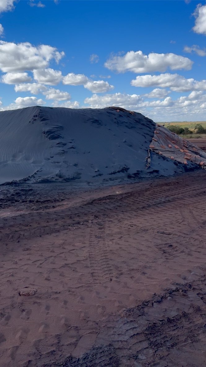 A covered stockpile of dark concentrate