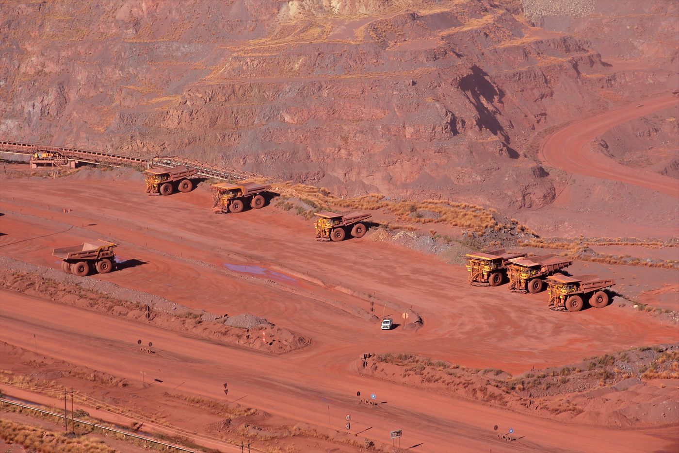 Haul trucks working the benches of a large open pit in red rock